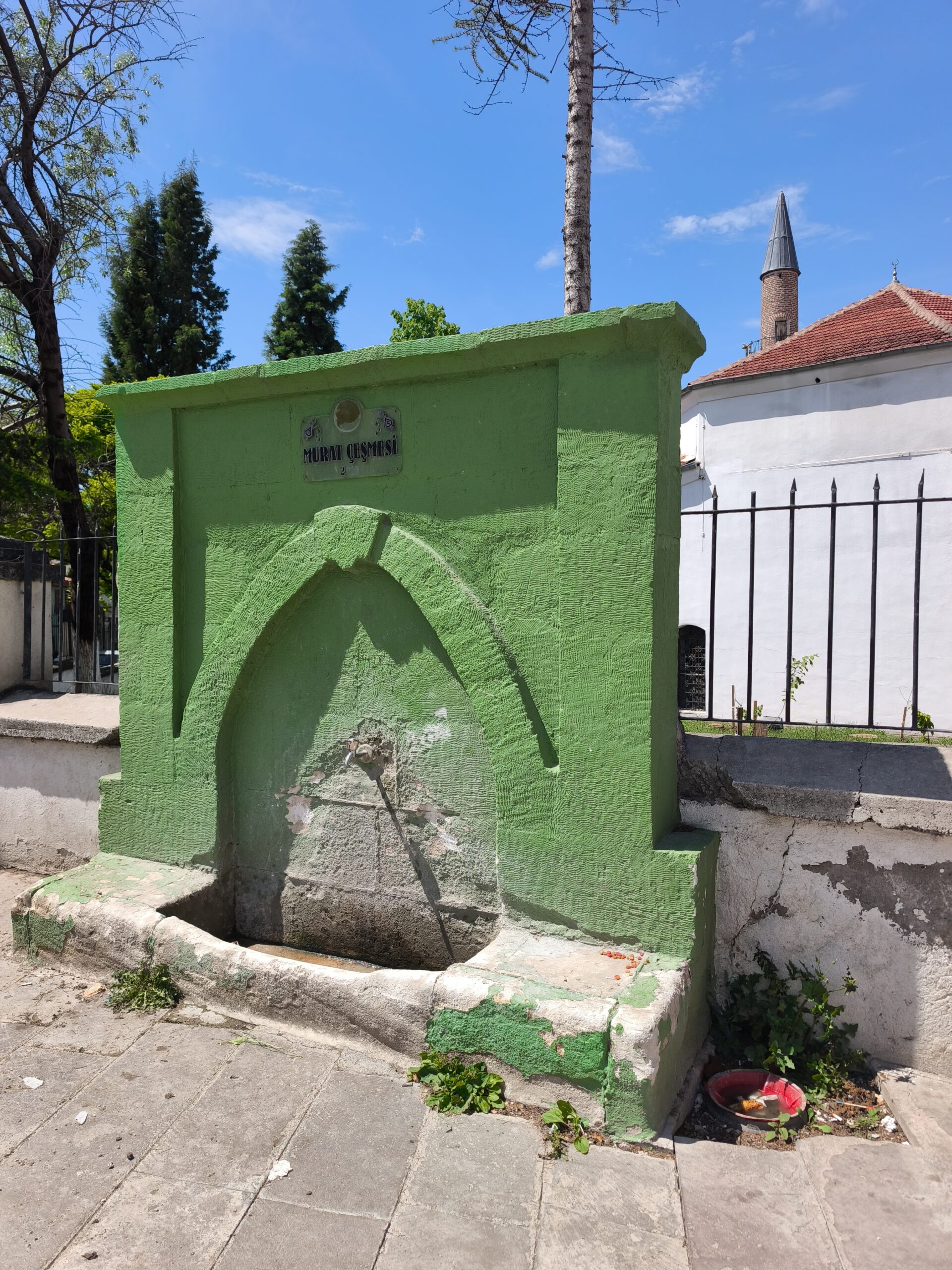Ak Camii duvarına bitişik halde bulunur.